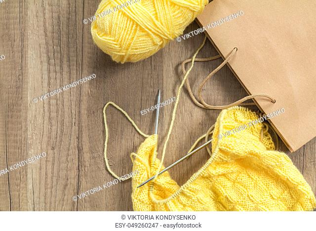 Light yellow knitting wool and knitting needles on wooden background. Top view.copy space. Knitted fabric and yarn on a wooden surface