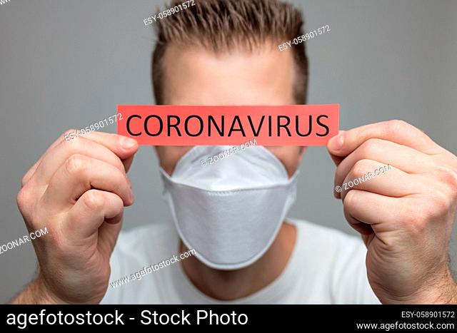 Worried man wearing a respiratory mask, holding the Coronavirus Covid-19 sign