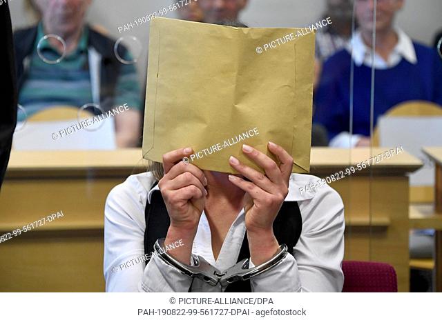 22 August 2019, Schleswig-Holstein, Itzehoe: The defendant sits in the courtroom with her face concealed at the start of a murder trial