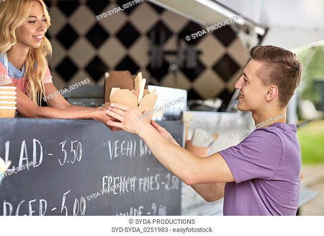 saleswoman at food truck serving male customer