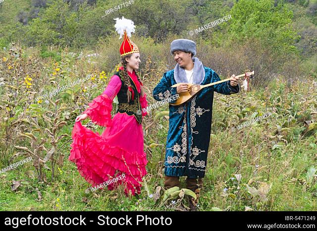 Kazakh man singing and playing dombra for a woman, Central Asia, Kazakh ethnographic village Aul Gunny, Talgar city, Almaty, Kazakhstan, Asia
