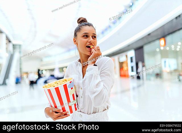 young woman holding popcorn in the mall background