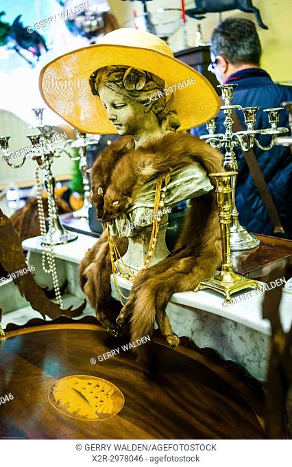 Animal pelts and a yellow hat adorn an artistic bust inside an antique shop in Bath, Somerset