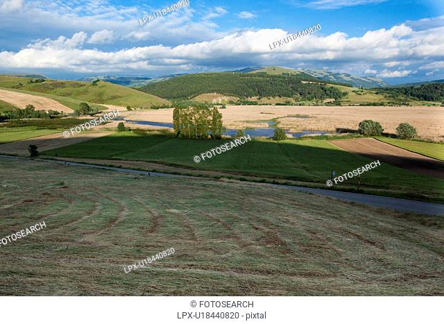 Italian farmland with rolling hills, road, river, on sunny spring afternoon