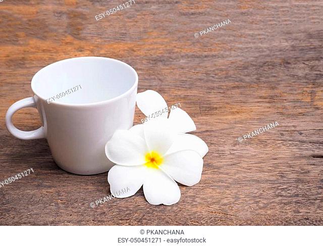 white plumeria flower and empty cup of coffee on wood background