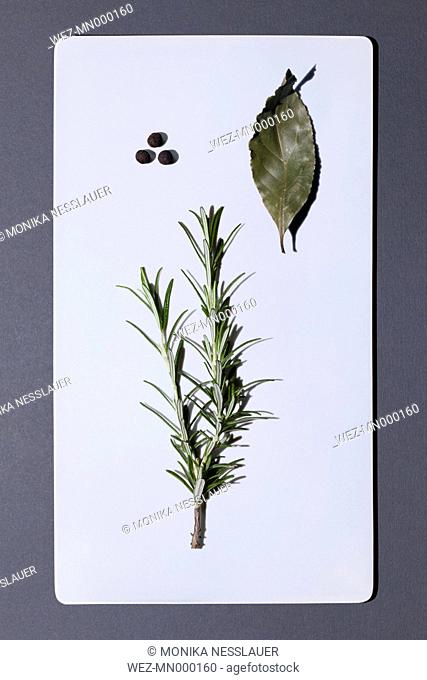 Bay leaf and twig of rosemary on white board
