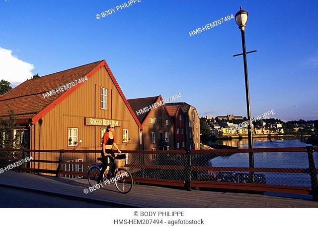 Norway, Sor-Trondelag County, Trondheim, young woman cyclin on Gamle Bybro old bridge