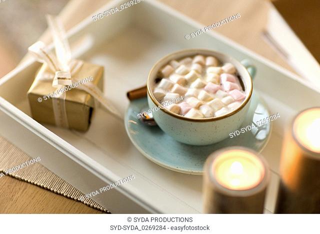 hot chocolate, christmas gift and candles on table