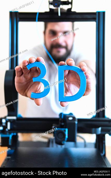 Male technician holding 3D printed text through machinery