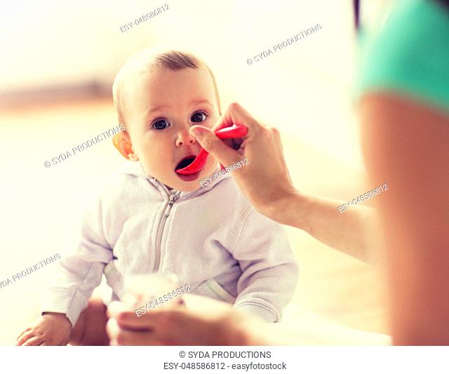 mother with spoon feeding little baby at home