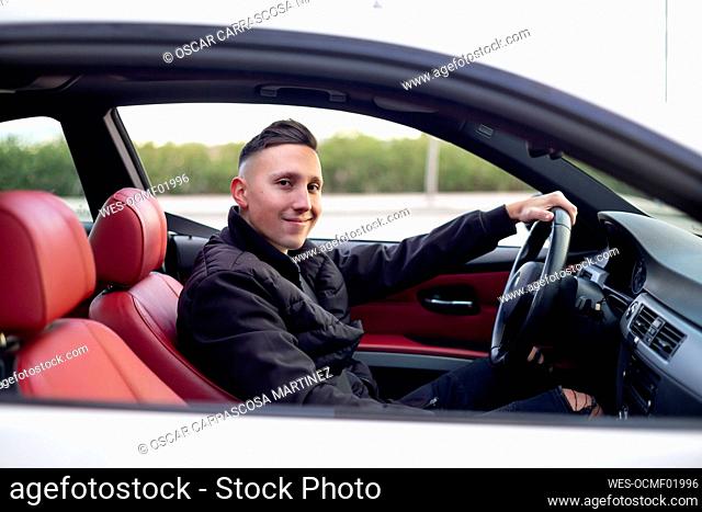 Young man smiling while sitting in car