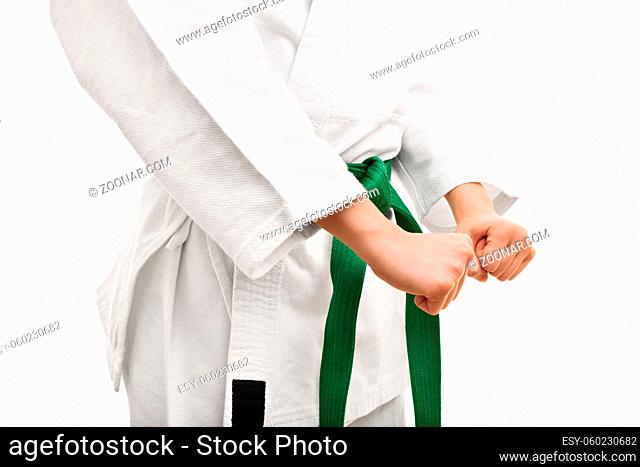 Combat readiness. Mid section of a young fighter in a kimono wth green belt, in a combat stance, isolated on white background