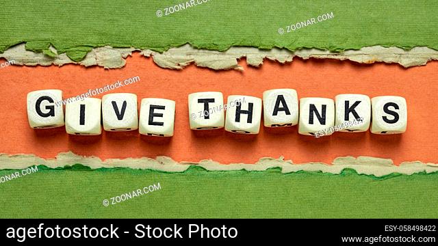 give thanks text in wooden letter cubes against abstract green and orange handmade paper banner, Thanksgiving concept