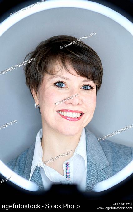 Smiling beautiful businesswoman seen through ring light