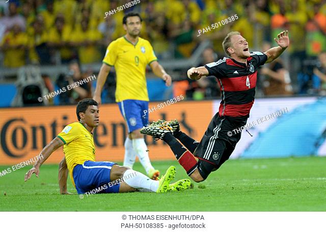 Germany's Benedikt Hoewedes (R) is tackled by Brazil's Paulinho during the FIFA World Cup 2014 semi-final soccer match between Brazil and Germany at Estadio...