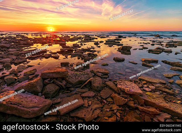 Beautiful sunrise over the sea. Many rocks at the front