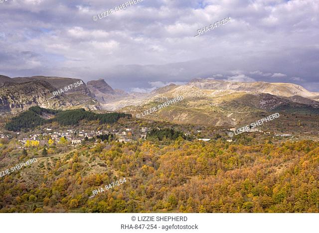 A little sunlight breaks through on a cloudy day above Tsepelovo and the Timfi mountain range, Epirus, Greece, Europe