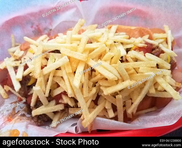 hot dog in basket covered with beef, onions, and fries