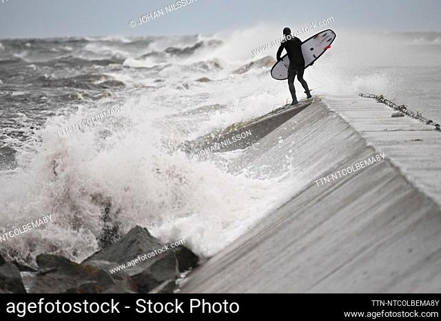 HÖLLVIKEN, SWEDEN 20231020 Surfers as waves and wind whip against the breakwater at Falsterbokanalen outside Kämpinge Strandbad on Friday evening