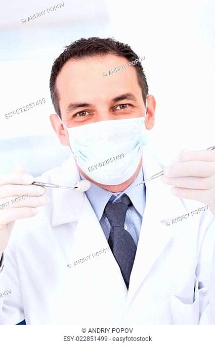 Portrait Of Male Dentist Holding Angled Mirror And Carver
