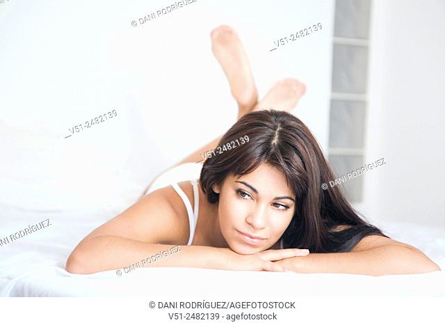 Portrait of a sensual and pensive young woman lying in the bed