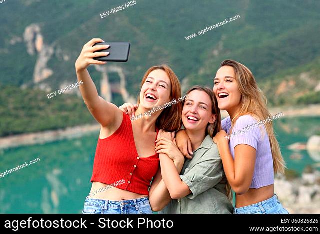 Funny friends taking selfies on smartphone in the mountain on summer vacation