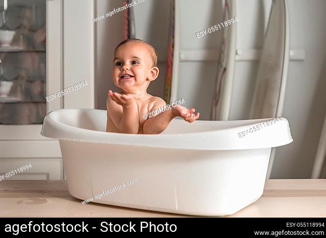 Adorable baby smiling in the bathtub gesturing with her hands