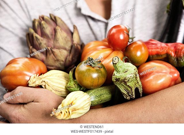 Italy, Tuscany, Magliano, Close up of young man holding different vegetables