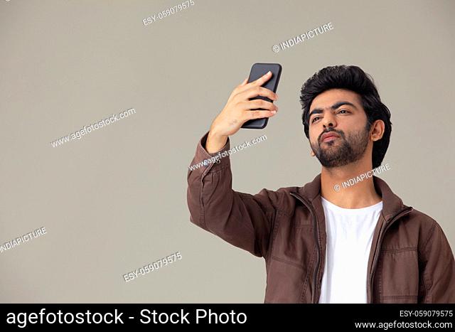A YOUNG MAN CLICKING SELFIE USING MOBILE PHONE