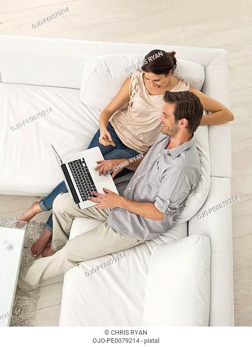 Couple sitting on sofa shopping online with credit card