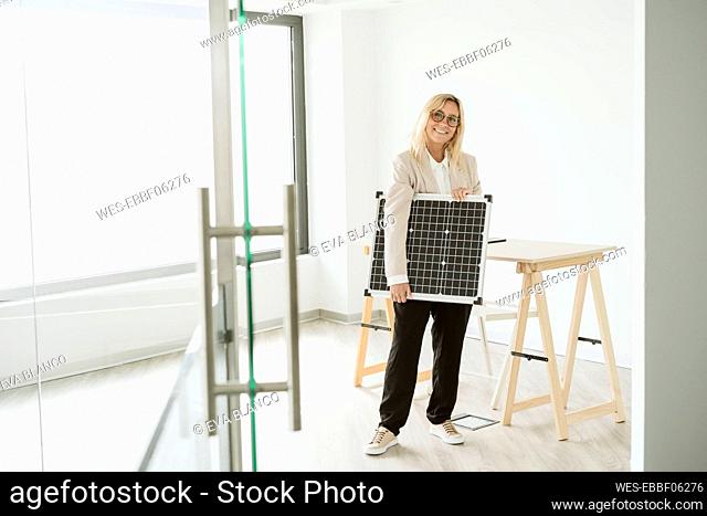 Woman holding solar panel in office