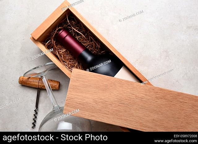 Cabernet Wine Box: A Red wine bottle in a wood box partially covered by its lid with a glass and corkscrew