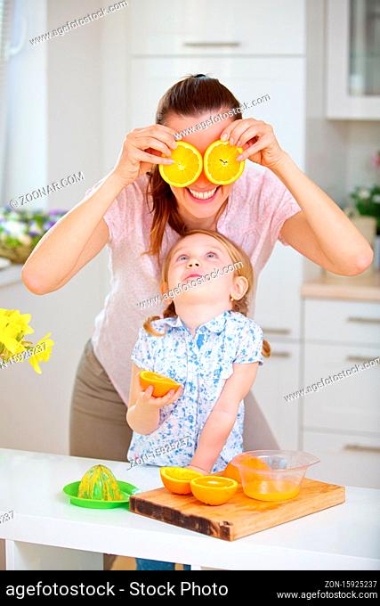 Familie mit Mutter und Tochter hat Spaß beim Saft pressen in der Küche