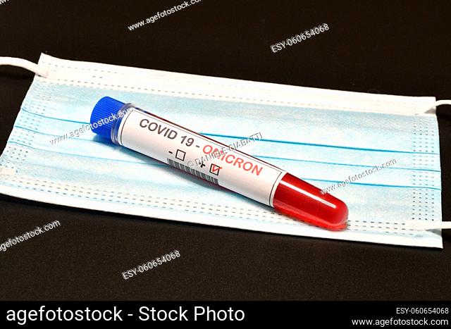 Blood tube for test detection of virus Covid-19 Omicron Variant with positive result on protection mask. Concept of protection from new variant of Omicron...