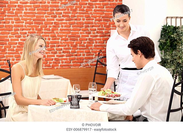 Waitress serving a young couple in a restaurant