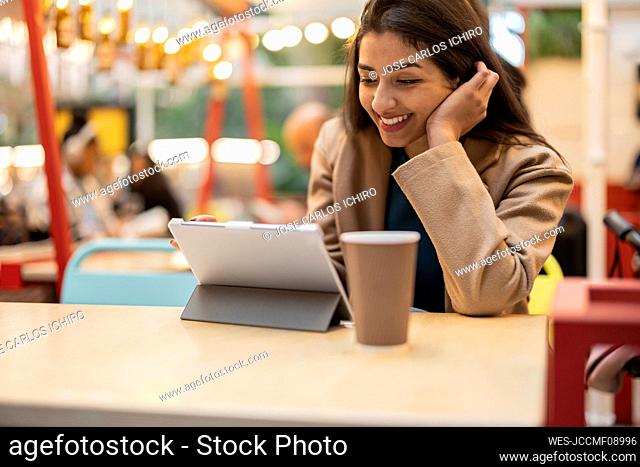 Happy young woman using tablet computer in cafe