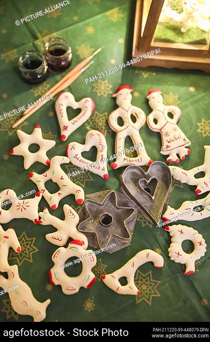 16 December 2021, Saxony, Werda: So-called Zuckermännle, historical Christmas biscuits from the Vogtland, lie on a table next to two historical cookie cutters