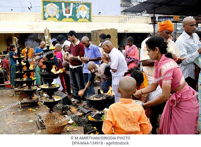 Devotees worshipping and offering coconut; camphor and flowers to Lord Venkateshwara (Balaji) in front of the huge oil lamps  at Tirumala temple; Tirupati ;...