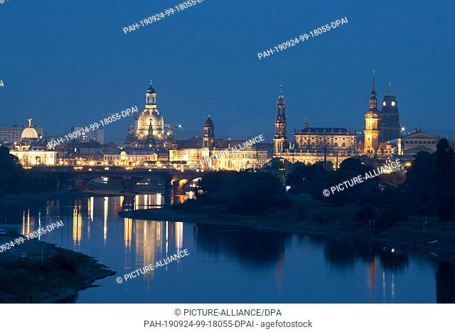 24 September 2019, Saxony: The buildings of Dresden's old town in front of the Elbe river are brightly lit at nightfall. Photo: Sebastian...