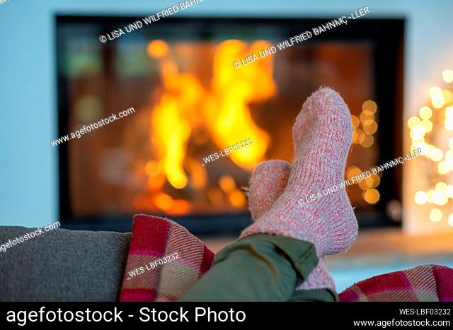 Legs of young woman wearing socks relaxing against fireplace at home