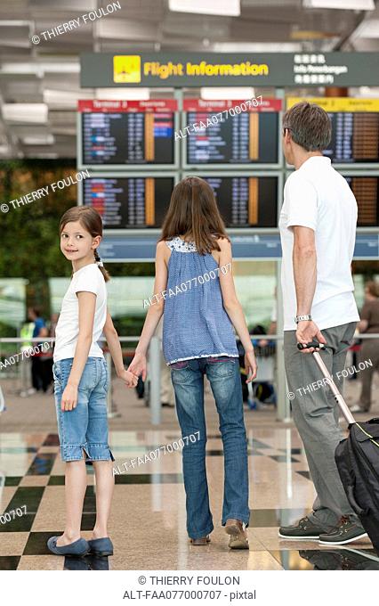 Family looking at arrival departure board in airport