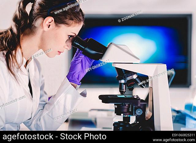 Life scientist researching in laboratory. Portrait of a attractive, young, confident female health care professional microscoping in hes working environment