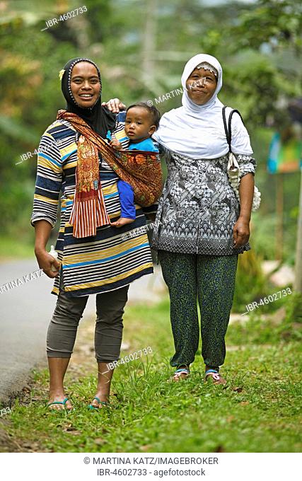 Muslim women, 37 and 45 years old, with toddler in sling, Losari Village, Magelang, Java, Indonesia