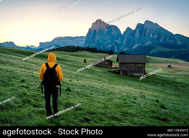 Man hiker enjoying sunrise at Alpe di Siusi, Dolomites mountains, Italy