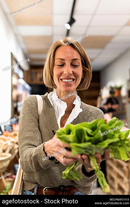Woman smiling while holding vegetable in supermarket