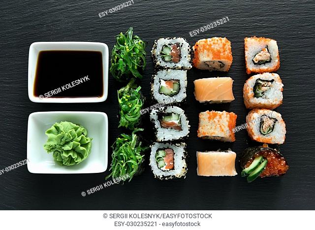 Delicious sushi set with wasabi and soy sauce on a slate table
