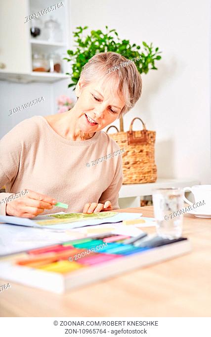 Alte Frau mit Demenz beim kreativen Malen mit Kreide als Therapie