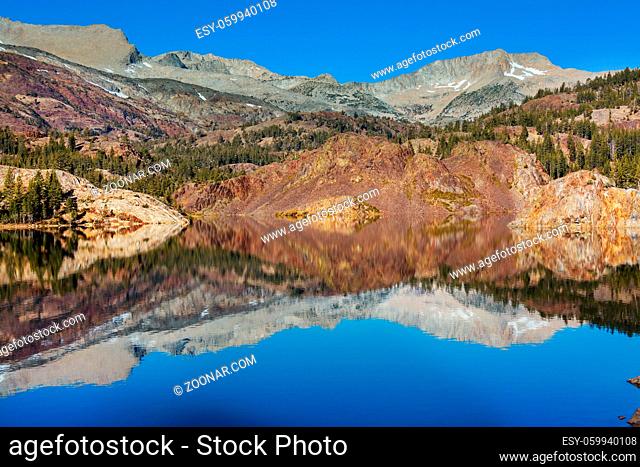 Serene scene by the mountain lake with reflection of the rocks in the calm water