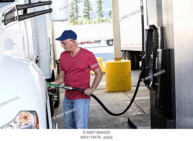 Caucasian man truck driver putting diesel fuel in his truck at a truck stop