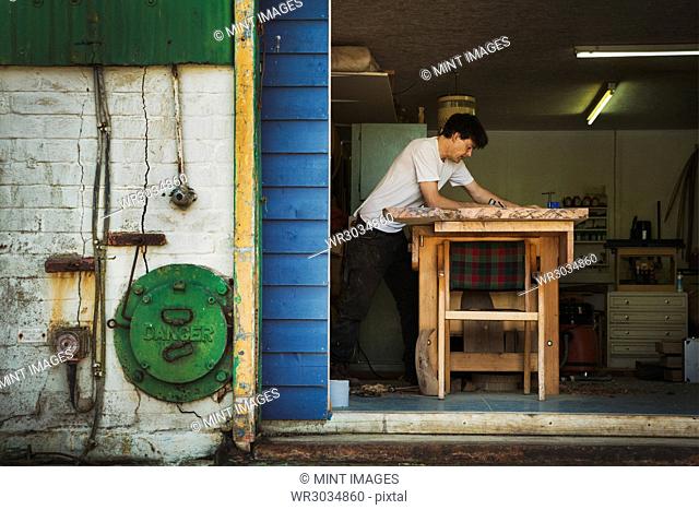 A craftsman working in his workshop, using tools on a block of wood